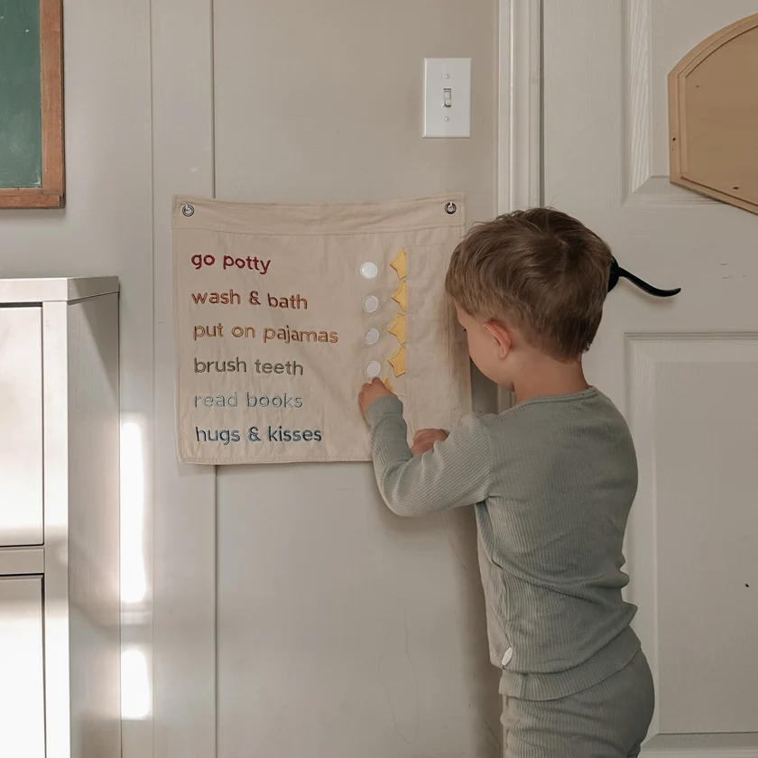Child interacting with a chart on a wall in a home setting